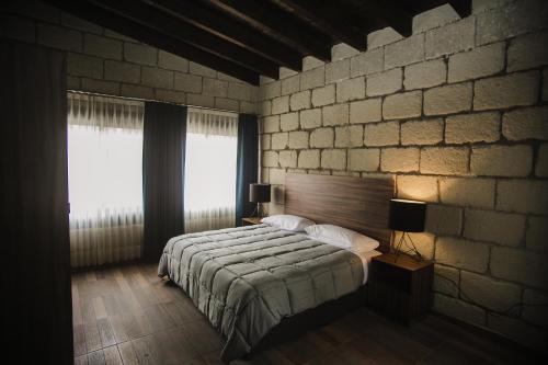 a bedroom with a bed and a brick wall at Real de Corralejo in San Miguel de Allende