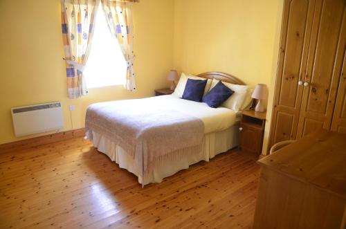 a bedroom with a bed with blue pillows and a window at Seaview Self-Catering in Allihies