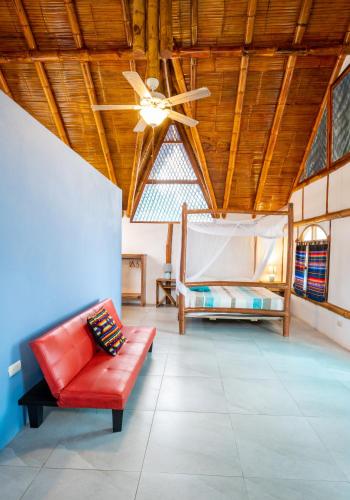 a living room with a red couch and a ceiling fan at Casa del Sol in Montañita