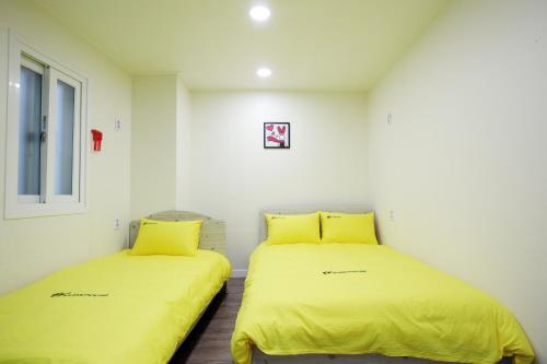 two beds in a room with yellow sheets at 24 Guesthouse Myeongdong Avenue in Seoul