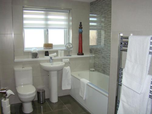 a bathroom with a toilet and a sink and a tub at Topsail, Falmouth in Falmouth