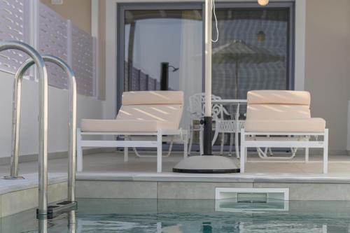 a pool with two chairs and an umbrella at Dionisos Suites in Lixouri