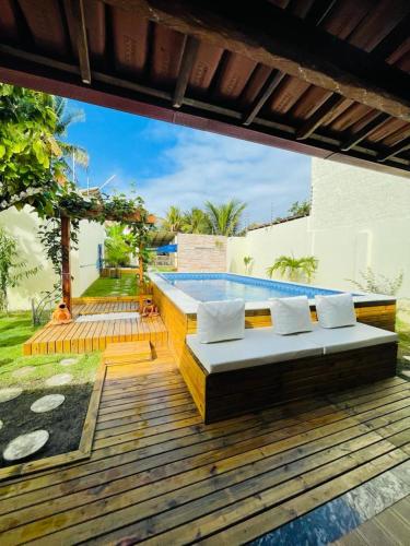 a wooden deck with a couch on top of a pool at Casa com Piscina in Canavieiras