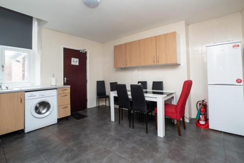 a kitchen with a table and chairs and a refrigerator at The New Mill Apartments in Newcastle upon Tyne