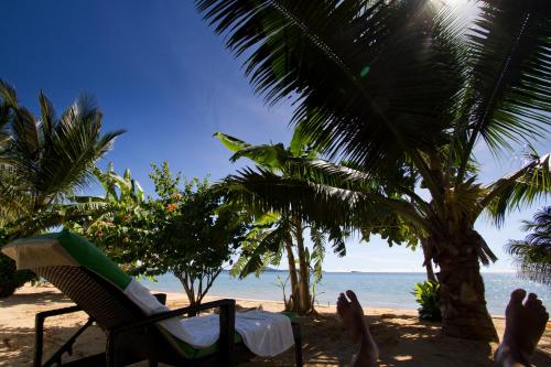 a beach with a chair and palm trees and the ocean at Anjiamarango Beach Resort in Nosy Be