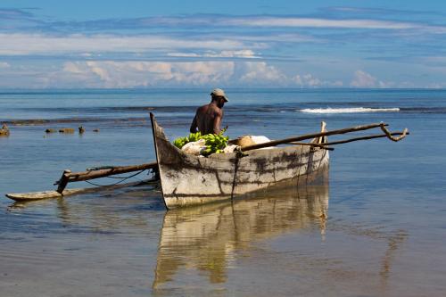 a man in a boat on the beach at Anjiamarango Beach Resort in Nosy Be