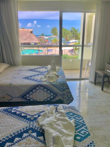 two beds in a room with a view of a beach at Ocean view Aquamarina in Cancún