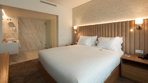 a large white bed in a hotel room at Douro Royal Valley Hotel & Spa in Riba Douro