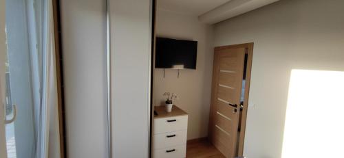 een slaapkamer met een tv aan de muur en een dressoir bij Apartament Ahoj in Jastrzębia Góra