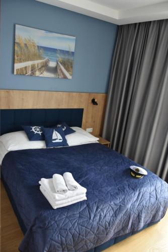 een slaapkamer met een blauw bed en handdoeken bij Apartament Ahoj in Jastrzębia Góra
