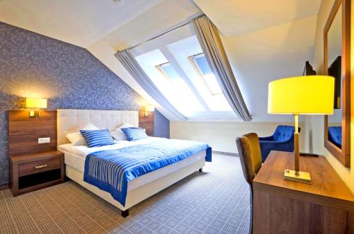 a bedroom with a bed and a desk and a window at Tristan Hotel & SPA in Kąty Rybackie