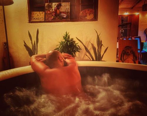 a man laying in a bath tub with his feet in the water at The Naked House - Hotel Nudista in Nemocón