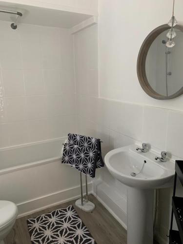a white bathroom with a sink and a mirror at Peveril Cottage in Castleton