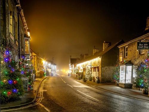 an empty street at night with christmas trees and lights at Peveril Cottage in Castleton