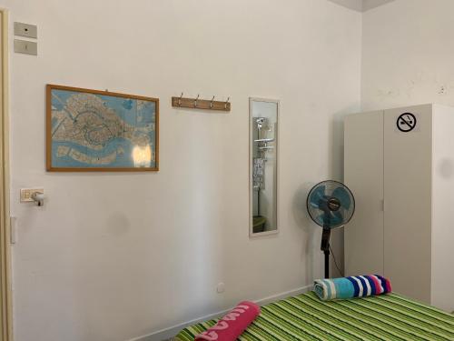 a room with a bed and a fan and a painting at Archie's House in Venice