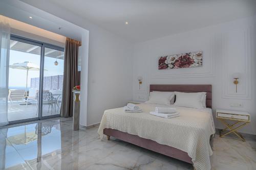 a white bedroom with a bed and a balcony at Dionisos Suites in Lixouri