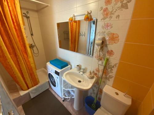 a bathroom with a sink and a toilet and a mirror at Bungalow Smiltele in Nida