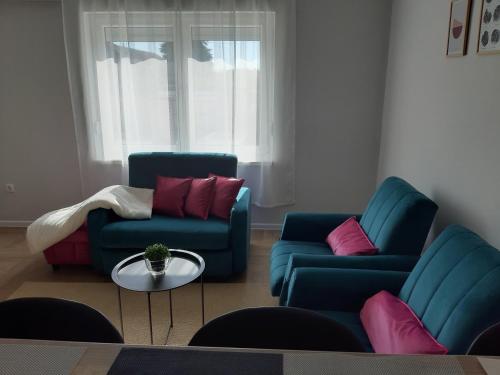 a living room with two blue chairs and a table at Apartments Manna Palic in Palić