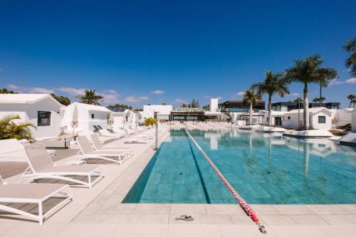a swimming pool with lounge chairs next to a resort at Club Maspalomas Suites & Spa - Adults Only in Maspalomas