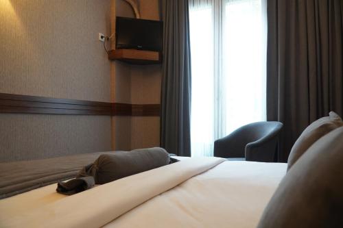 イスタンブールにあるBern Hotelのベッド1台、椅子、窓が備わる客室です。