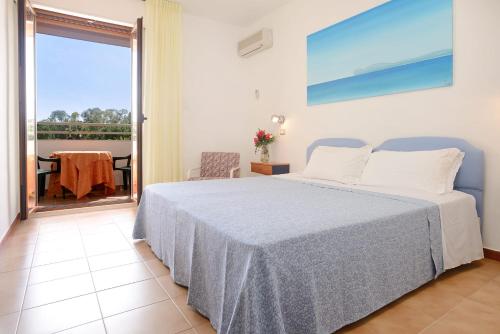 a bedroom with a bed and a balcony with a table at Hotel Oasis in Alghero