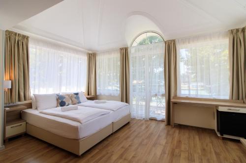 a bedroom with a large bed and large windows at Villa Marina Inn in Siófok