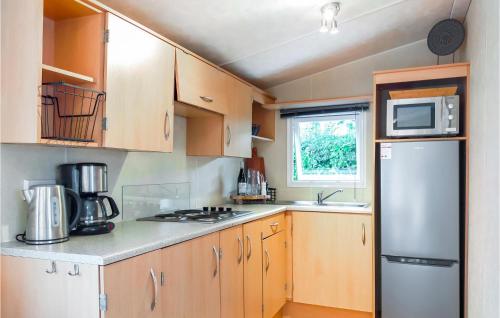 a small kitchen with wooden cabinets and a refrigerator at 2 Bedroom Lovely Home In Heinkenszand in Heinkensand