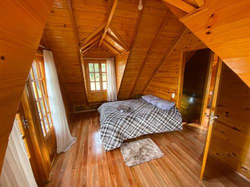 Cabana Refúgio da Serra في بوم ريتيرو: غرفة نوم بسرير في كابينة خشبية