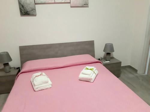 a bedroom with a pink bed with two towels on it at Casa vacanza Viola in Trapani