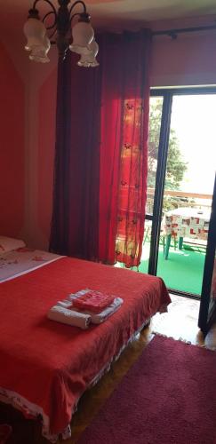a bedroom with a bed with a red blanket and a window at Guest House Cinderella in Herceg-Novi