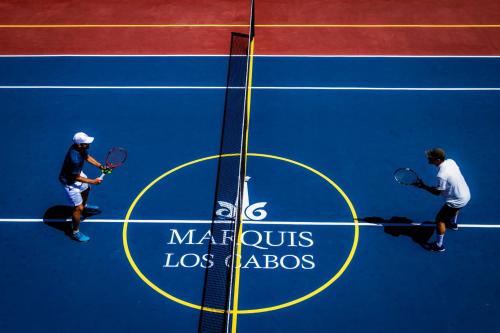 a man holding a tennis racquet on top of a tennis court at Marquis Los Cabos, an All - Inclusive, Adults - Only & No Timeshare Resort in San José del Cabo