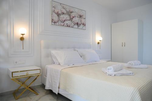 a white bedroom with two beds with towels on them at Dionisos Suites in Lixouri
