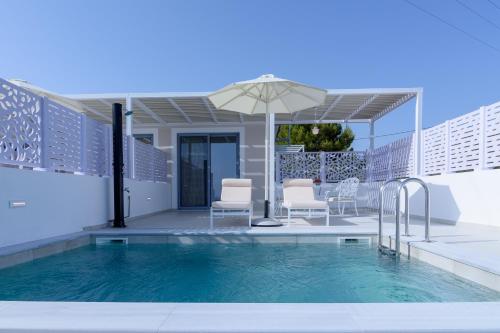 a swimming pool with chairs and an umbrella at Dionisos Suites in Lixouri