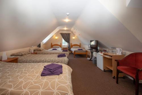 a attic room with two beds and a desk at The William IV in Norwich