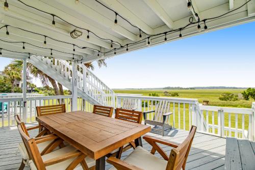 a porch with a wooden table and chairs on a deck at Belle Mare in Folly Beach