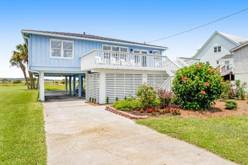 a blue house with a balcony and a yard at Belle Mare in Folly Beach