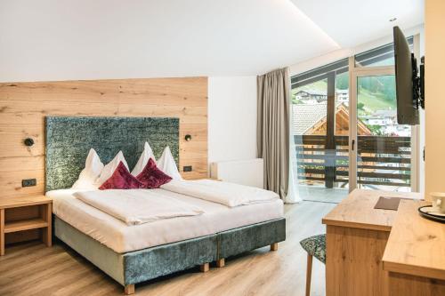 sypialnia z dużym łóżkiem, biurkiem i biurkiem w obiekcie Garni Hotel Miara - Your Dolomites Home w mieście Selva di Val Gardena