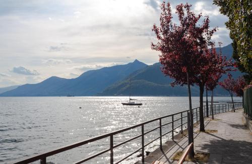 a boat in the water next to a fence at Casa del Borgo "Aria & Acqua" sul Lago Maggiore in Maccagno Inferiore