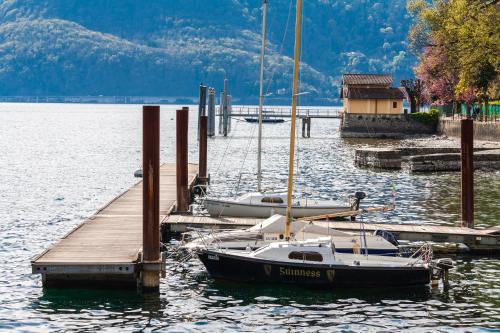 two boats are docked at a dock in the water at Casa del Borgo "Aria & Acqua" sul Lago Maggiore in Maccagno Inferiore