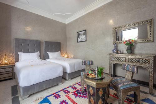 een slaapkamer met 2 bedden, een open haard en een spiegel bij Riad Salman in Marrakesh