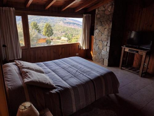 ein Schlafzimmer mit einem Bett und einem großen Fenster in der Unterkunft Casa Rincón Radales in San Martín de los Andes