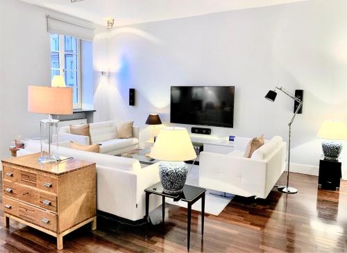 Il comprend un salon doté d'un mobilier blanc et d'une télévision à écran plat. dans l'établissement Luxury Suites & Apartments MONDRIAN Old Town, à Varsovie
