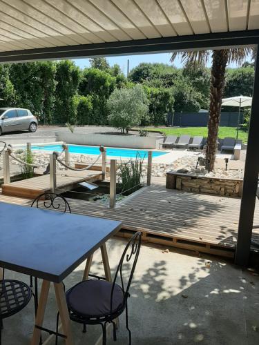 a patio with a table and chairs and a swimming pool at Les chambres d'hôtes de la croix bleue in Murinais