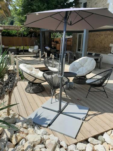 a patio with a table and chairs and an umbrella at Les chambres d'hôtes de la croix bleue in Murinais