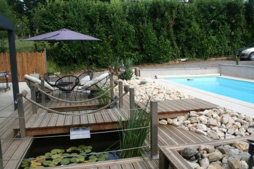 a backyard with a pool and a deck with an umbrella at Les chambres d'hôtes de la croix bleue in Murinais