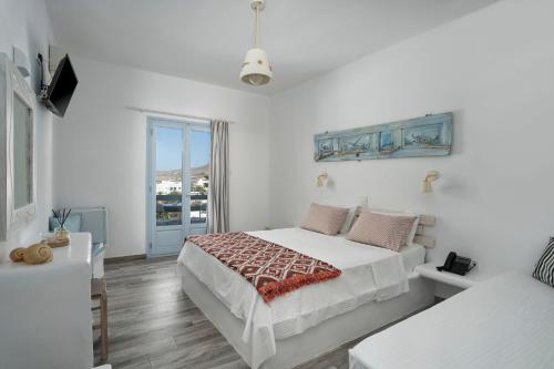 a white bedroom with a bed and a window at Hotel Iris in Naousa