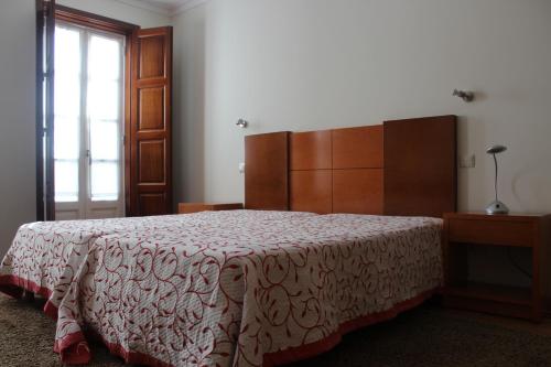 a bedroom with a bed and a dresser and a window at Guesthouse Muralhas do Mino in Monção