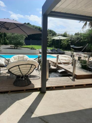 a deck with a table and an umbrella next to a pool at Les chambres d'hôtes de la croix bleue in Murinais