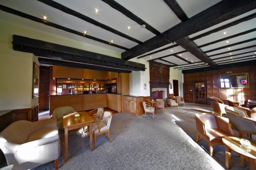 a lobby of a hotel with tables and chairs at voco Letchworth Hall by IHG in Letchworth