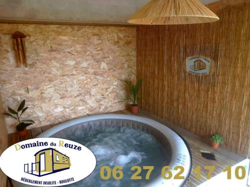 a round tub in a bathroom with a stone wall at Roulotte et Jacuzzi de Rachel au Domaine du Reuze in Winnezeele
